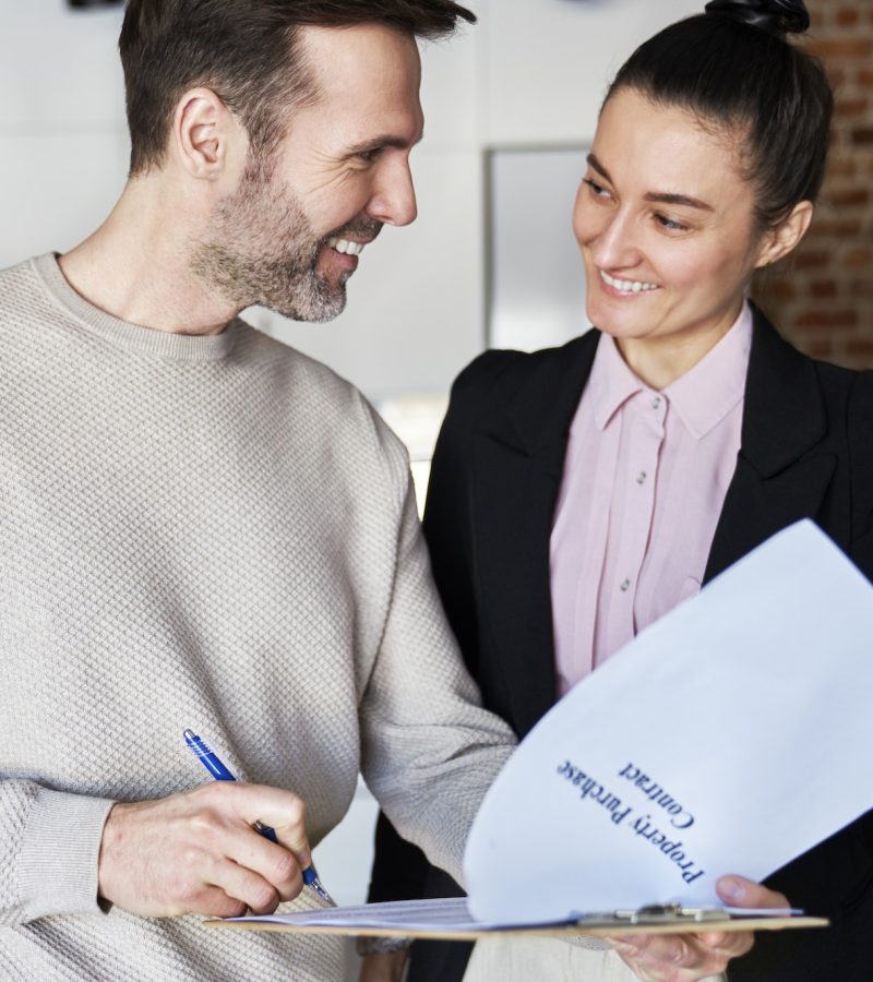 Happy man with estate agent signing contract of new apartment